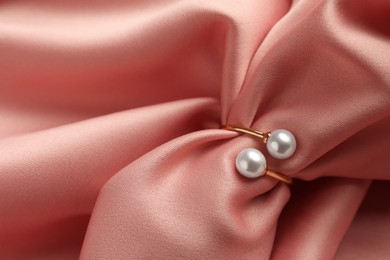 Elegant golden ring with pearls on pink silk, closeup