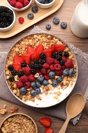 Healthy muesli served with berries on wooden table, flat lay