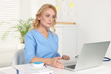 Doctor with laptop consulting patient in clinic. Online medicine concept