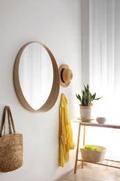Round mirror with wooden frame on white wall in light room