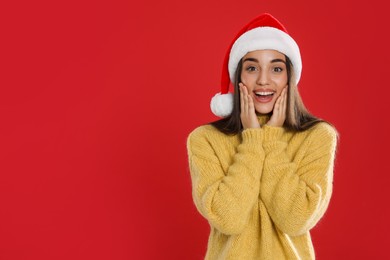 Excited woman in Santa hat on red background, space for text. Christmas countdown