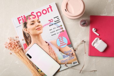Sports magazine, smartphone and women's accessories on light table, flat lay