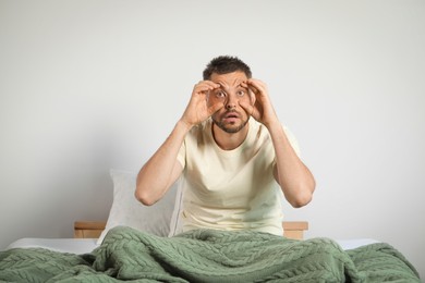 Sleepless man sitting on bed at home