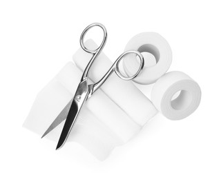 Medical bandage rolls, sticking plaster and scissors on white background, top view