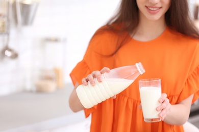 Beautiful young woman drinking milk in kitchen