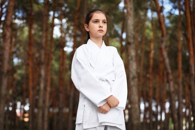 Cute little girl in kimono in forest. Karate practicing