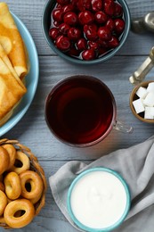 Photo of Flat lay composition with aromatic tea and treats on light blue wooden table