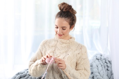 Portrait of beautiful teenage girl in warm cozy sweater knitting at home