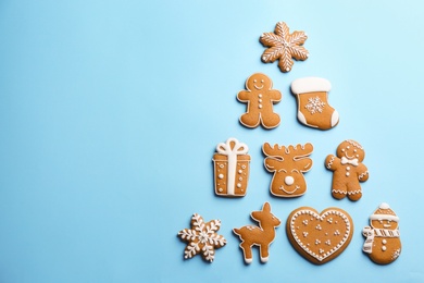 Photo of Delicious gingerbread cookies arranged in shape of Christmas tree on light blue background, flat lay. Space for text