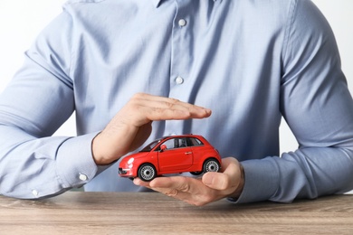 Male insurance agent holding toy car, closeup