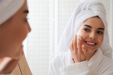 Photo of Woman using silkworm cocoon in skin care routine near mirror at home