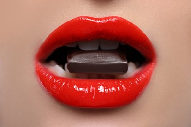 Photo of Young woman with beautiful lips eating chocolate, closeup