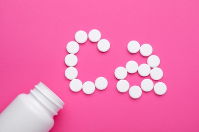 Calcium symbol made of white pills and open bottle on pink background, flat lay