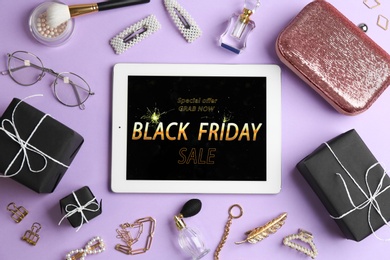 Flat lay composition with tablet, gifts and accessories on violet background. Black Friday sale