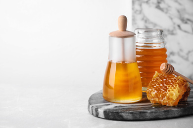 Tasty organic honey on light grey table, space for text