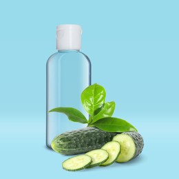 Bottle of micellar cleansing water, fresh cucumbers and green leaves on blue background. Makeup remover