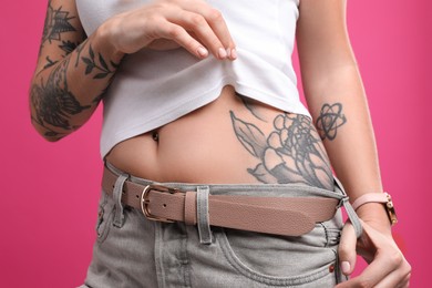 Woman with tattoos on body against pink background, closeup