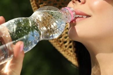 Young woman drinking water outdoors, closeup. Refreshing drink