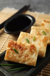 Photo of Delicious turnip cake with green onion on 'mat, closeup