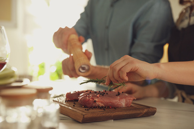 Lovely young couple cooking meat together in kitchen, closeup