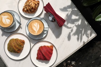 Photo of Delicious croissants and coffee on white marble table, flat lay