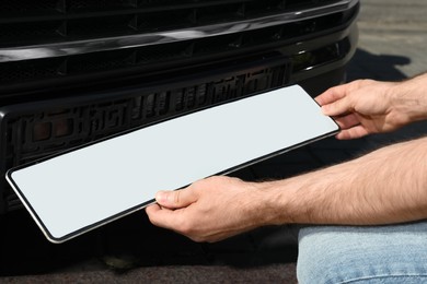 Man installing vehicle registration plate outdoors, closeup