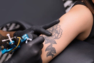 Photo of Professional artist making tattoo in salon, closeup