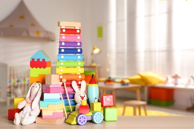 Set of different bright toys on wooden table in children's room. Space for text