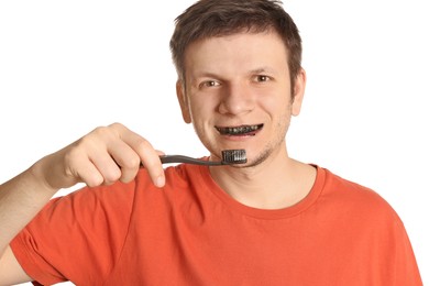 Man brushing teeth with charcoal toothpaste on white background