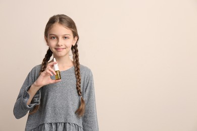 Sick little girl with nasal spray on beige background. Space for text