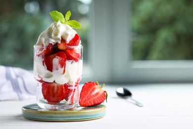 Delicious strawberries with whipped cream served on white wooden table indoors. Space for text