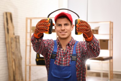 Worker holding safety headphones indoors, focus on hands. Hearing protection device