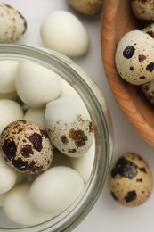 Photo of Unpeeled and peeled boiled quail eggs on white table, flat lay
