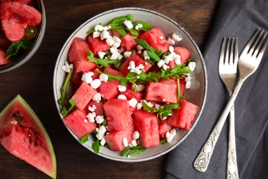 Delicious salad with watermelon, cheese and arugula on wooden table, flat lay