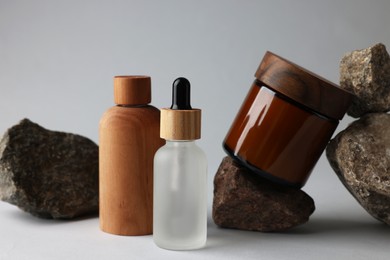 Different bottles, jar and stones on grey background, closeup