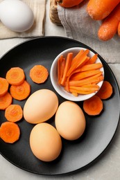 Photo of Naturally painted Easter eggs on light grey table, flat lay. Carrot used for coloring