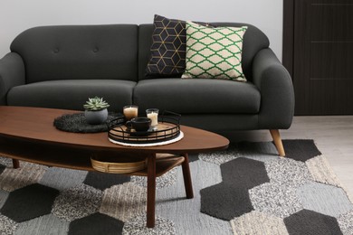 Sofa and freshly brewed coffee with decorative elements on wooden table in living room