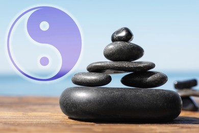 Stack of stones on wooden table outdoors and Ying Yang symbol. Feng Shui philosophy 
