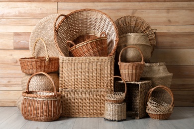 Many different wicker baskets made of natural material on floor near wooden wall
