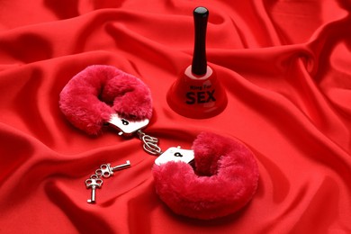 Photo of Handcuffs, keys and bell with text Ring For Sex on red fabric