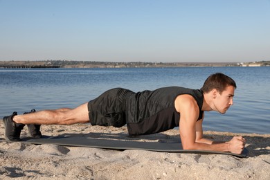 Sporty man doing plank exercise on beach