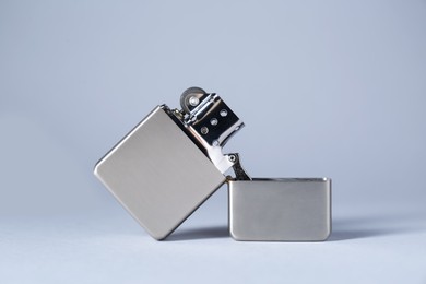 Photo of Metallic cigarette lighter on light gray background, closeup