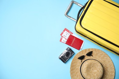 Flat lay composition with passport, tickets and travel items on light blue background. Space for text