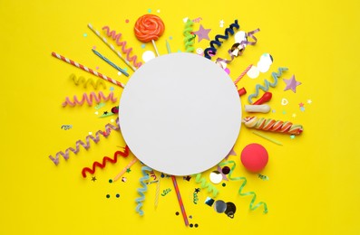 Photo of Flat lay composition with blank card and different party accessories on yellow background, space for text. Birthday surprise