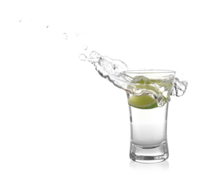 Splashing Mexican Tequila in shot glass with lime slice isolated on white
