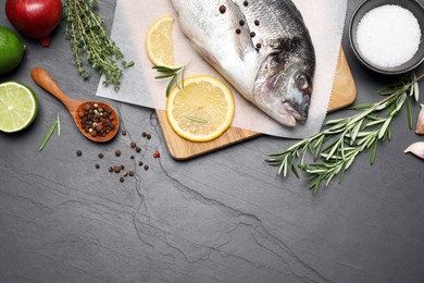 Flat lay composition with fresh raw dorado fish and ingredients on black table, space for text