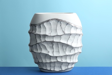 Stylish empty ceramic vase on table against light blue background