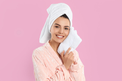 Young woman wiping face with towel on pink background