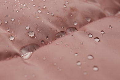 Pink waterproof fabric with water drops as background, closeup