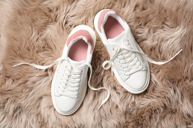 Pair of stylish shoes with laces on faux fur, flat lay